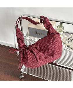 Detailed close-up of red checkered canvas bag with pleated design and side bow tie decor