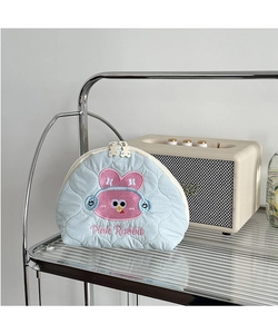 Close-up of blue quilted makeup bag with pink rabbit embroidery and bear zipper puller
