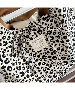 Detail shot of leopard print corduroy tote bag featuring vintage magazine textile label