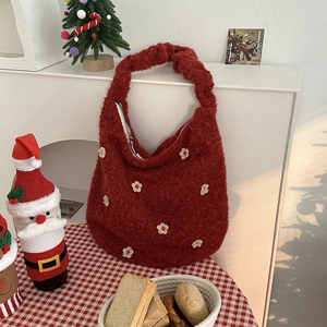 Detail der roten Plüsch-Schultertasche mit weicher Fleece-Textur und Blumenapplikationen