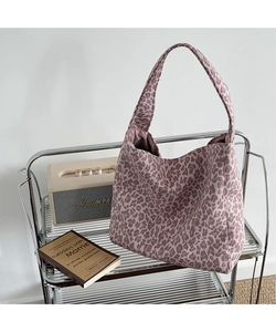 Detail view of the pink leopard print tote bag placed in a cozy home interior setting