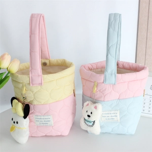 Detail of quilted bucket bags with plush charms and soft wavy stitching patterns