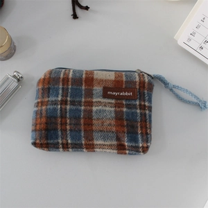 Detail view of Scottish plaid coin purse featuring a leather logo tag and blue woven zipper pull