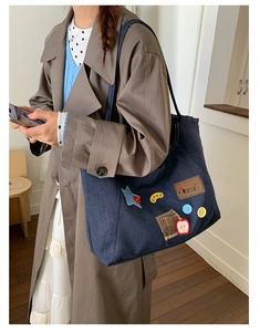 Detail of blue denim tote bag with colorful star buttons and GOOD patch embroidery