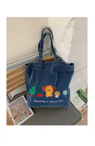 Detail view of denim tote bag with colorful dog and mushroom embroidery and text
