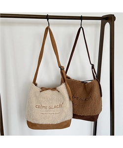 Detail of plush suede crossbody tote bags featuring embroidered French lettering and straps