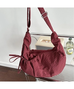 Detail of burgundy checkered hobo bag with drawstring sides and adjustable strap