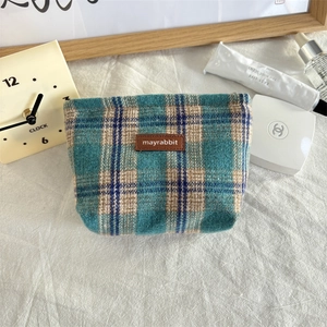 Detailopname van de blauw-beige geruite gebreide make-uptas met luxe lederen merklogo