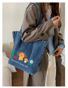 Close-up of blue denim tote bag featuring colorful dog embroidery and nature park text