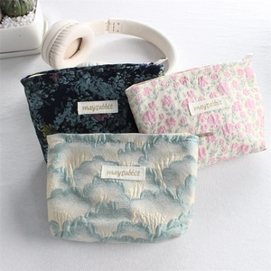 Three floral canvas cosmetic bags with jacquard textures and metal zipper detail