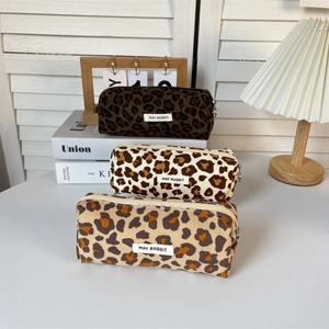 Detail of leopard print cosmetic bags with metal zippers and brand labels on books