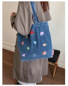 Detail of blue denim tote bag with colorful sea creature embroidery on a shoulder strap