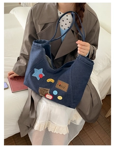 Close-up of vintage denim tote bag featuring colorful patch embroidery and star details