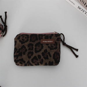 Detail of leopard print plush coin purse with leather label and woven rope zipper pull