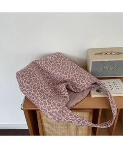 Detail of pink leopard print tote bag placed on wooden furniture with vintage props