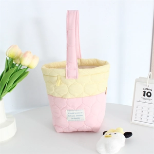 Quilted pastel pink and yellow cloud bucket bag with soft cotton handle in a cozy setting
