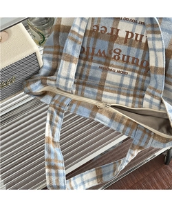 Detail view of plaid wool tote bag showing zipper closure and textured check fabric