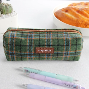 Detail of vintage green plaid pencil case with brown leather tag and metal zipper