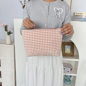 Detail van rood geruite make-uptas met geplooide textuur en May Rabbit-merklabel