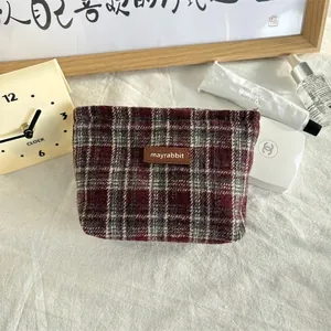 Detail van rood geblokte cosmetische tas met leren patch op zachte linnen achtergrond