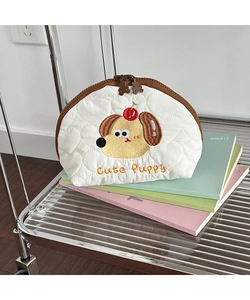 Detailed embroidery of a cute puppy and cherry on a quilted cream cosmetic bag