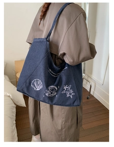 Detail of vintage denim tote bag showing the ocean shell prints and white slogan text