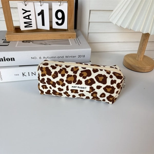 Detail of leopard print canvas makeup bag with zipper and brand label on a cozy desk