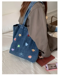 Detail of colorful marine life embroidery on deep blue denim canvas tote bag with strap