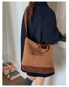 Detail of shearling and suede tote bag with French embroidery worn by model