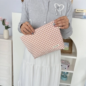 Detail van rood-wit geblokte make-uptas met May Rabbit label in de hand