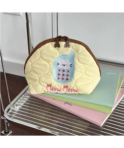 Detail of yellow quilted makeup bag with cat embroidery and bear-shaped zipper puller