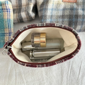 Close-up van vintage rode geruite tweed make-uptas met zilveren ritssluiting en voering