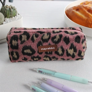 Detail view of pink leopard print plush pencil case with brown leather logo patch