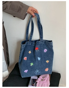 Detailed close-up of blue denim tote bag featuring ocean theme jellyfish embroidery