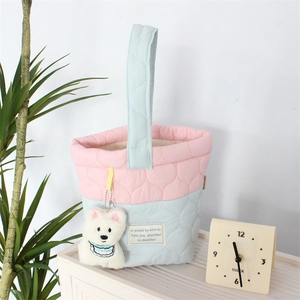 Detail of pink and blue quilted cloud bag with cute plush bear charm in a lifestyle setting