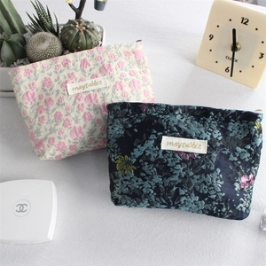 Floral canvas pouches in white and navy with zipper closures for makeup storage