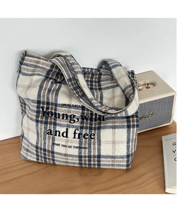 Detail of vintage plaid tote bag with embroidered letters on a wooden surface
