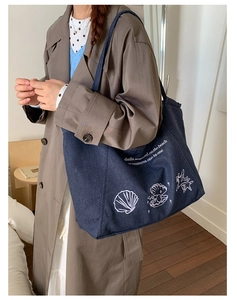 Detail of vintage denim tote bag with ocean shell embroidery and casual shoulder strap