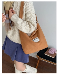 Detail of warm brown suede tote bag with drawstring and SEEYOU label on a sweater model