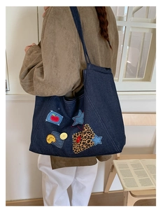Detail of vintage denim tote bag featuring colorful patchwork and decorative yellow buttons