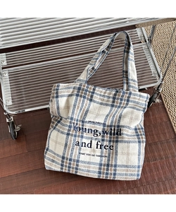 Close-up of vintage plaid wool tote bag featuring embroidered slogan and woven texture