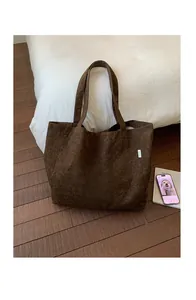Detail of dark brown canvas tote bag with letter print on vintage wood floor