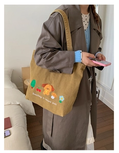 Close-up of yellow canvas tote bag featuring cute dog embroidery and wide shoulder strap