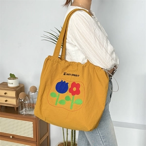 Detail der gelben Kordelzug-Tasche mit Blumenmustern und MAY RABBIT Kaninchen-Icon