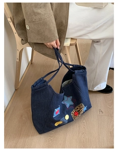 Detail of vintage denim tote bag with star patches and leopard print accents on a chair