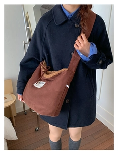 Detail of suede crossbody bag with fleece trim and ribbon bow on blue wool coat