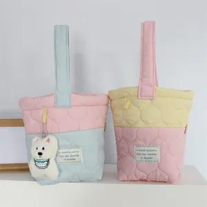 Detail of quilted cloud bucket bags in pink-blue contrast with cute bear pendant