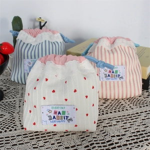 Detail of cute lace drawstring bags with heart and stripe patterns on a lace cloth
