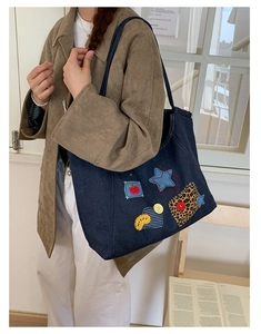 Detail of vintage denim tote bag showing colorful patches and large capacity design