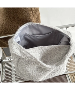 Detail of grey plush bucket bag showing soft faux fur texture and satin lining with inner pocket